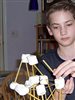 A home-schooled boy building a structure with marshmallows and sticks.