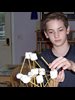A home-schooled boy building a structure with marshmallows and sticks.