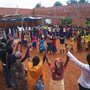 Villagers, both Tutsi and Hutu, gather to celebrate at the building site of a community center