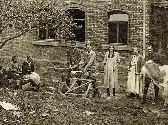 A black and white photograph of Eberhard and Emmy Arnold with fellow members of the first Bruderhof community in 1920s Sannerz, Germany.