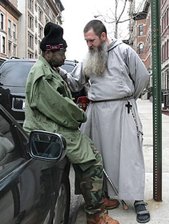 A friar counsels a woman on the sidewalk