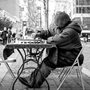 An elderly man playing chess by himself on a New York City street.