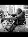An elderly man playing chess by himself on a New York City street.