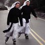 two nuns rollerblading down a street