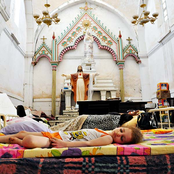a young girl sleeping on a mattress in a church
