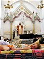 a young girl sleeping on a mattress in a church