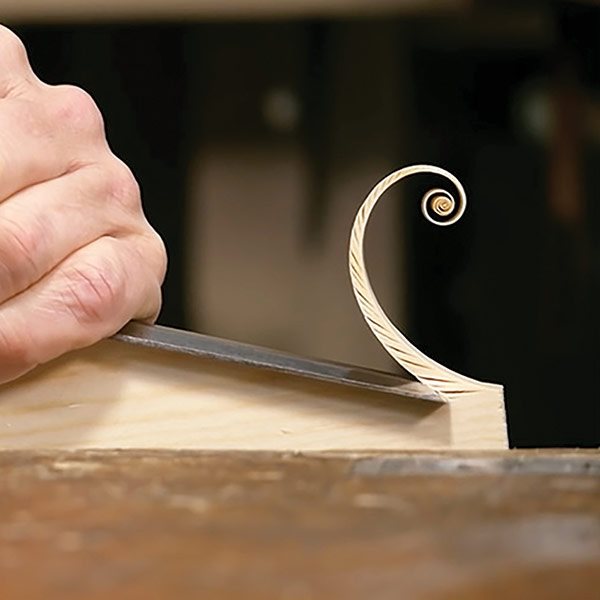 a curl of light colored wood at the end of a chisel