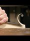 a curl of light colored wood at the end of a chisel