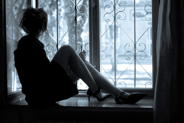 Girl in high heels sitting on a windowsill and looking out. 
