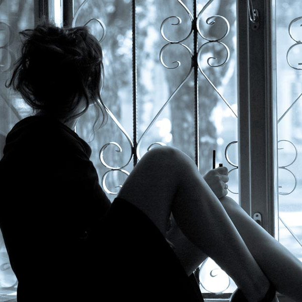 Girl in high heels sitting on a windowsill and looking out. 