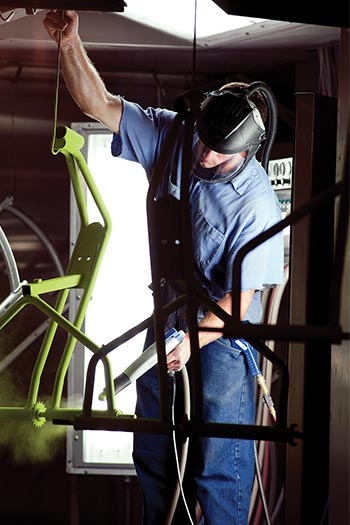 a man spraying green paint on a metal frame