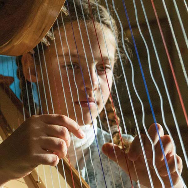 Marlys plays the harp her father made