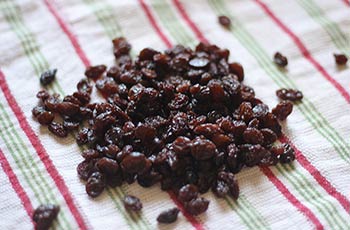 a pile of raisins on a red, green, and white striped cloth