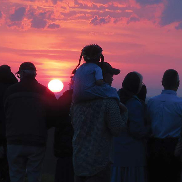 silhouettes of people in front of a sunrise