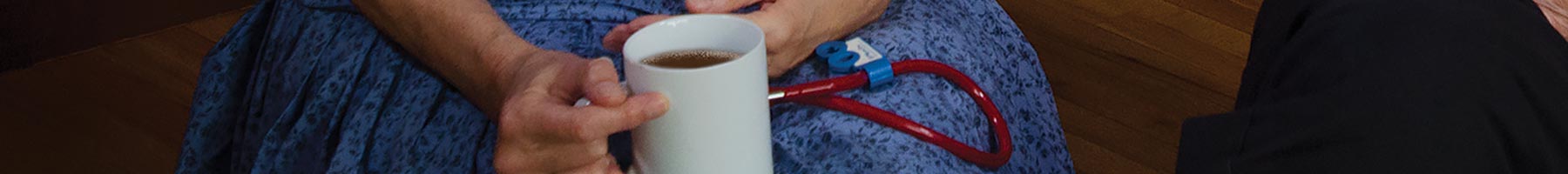 hand holding a coffee mug beside a stethoscope
