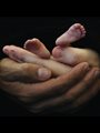 two hands holding a baby's feet