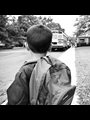 a black and white photograph of a boy looking at a school bus