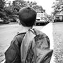 a black and white photograph of a boy looking at a school bus