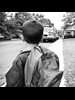 a black and white photograph of a boy looking at a school bus