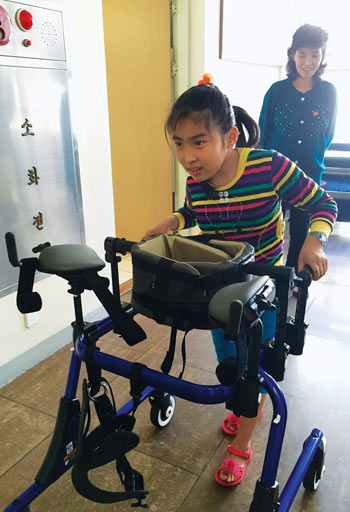 A child learns how to walk using a gait trainer donated by the Bruderhof, the community behind Plough.