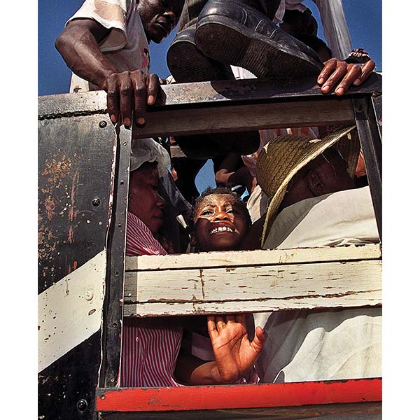 a boy in an open-back bus surrounded by many people: Carl Juste, Crushed, Port-au-Prince, Haiti