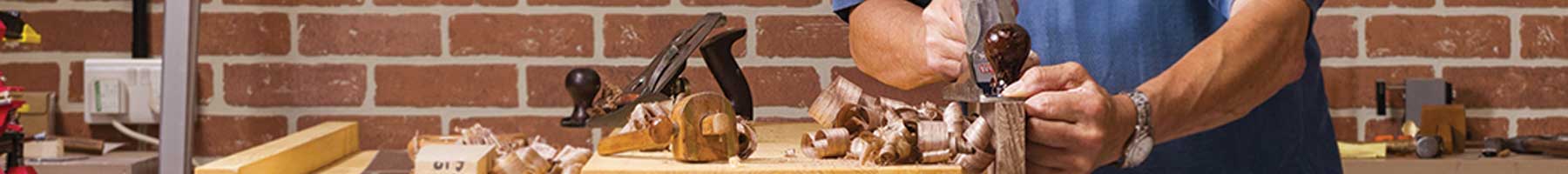 A carpenter planing in his workshop