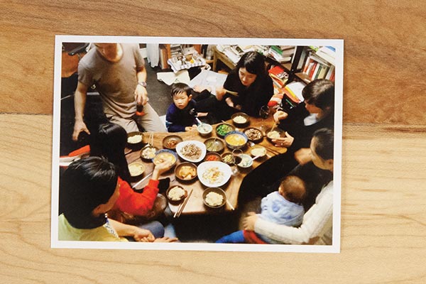 photograph on a wooden table of families eating a Korean meal