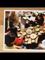 photograph on a wooden table of families eating a Korean meal