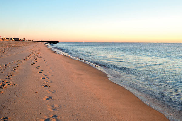 sunset on a beach with footprints in the sand