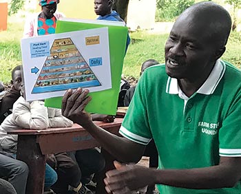 Joseph Malish teaching FARM STEW’s food pyramid to refugees during a  training.