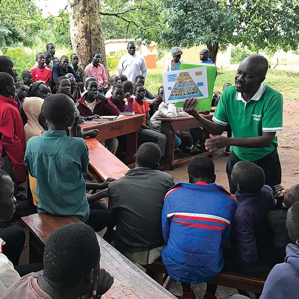 Joseph Malish teaching FARM STEW’s food pyramid to refugees during a  training.