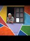 old man looking out of a window in a colorful wall