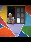 old man looking out of a window in a colorful wall