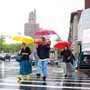 people walking across a street in New York with brightly colored umbrellas in the rain