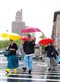 people walking across a street in New York with brightly colored umbrellas in the rain