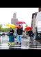 people walking across a street in New York with brightly colored umbrellas in the rain