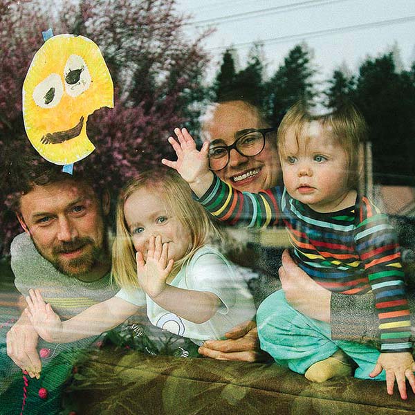 a father and mother and two daughters, photographed at their living room window