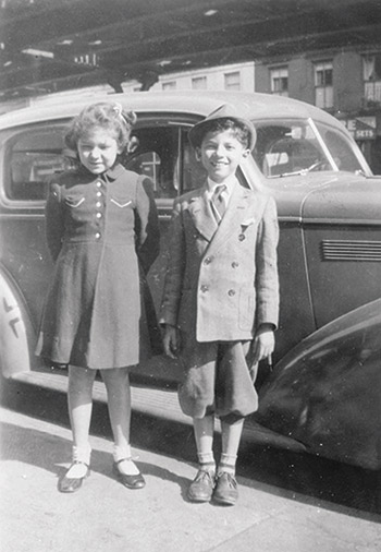 Foto blanco y negro de dos niños parados al lado de un auto