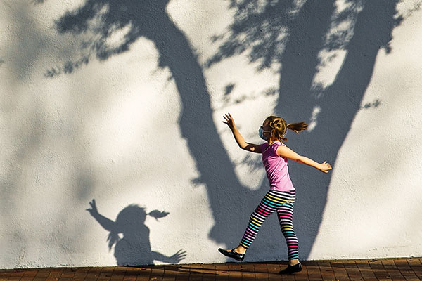 photo of a little girl walking happily on a sidewalk
