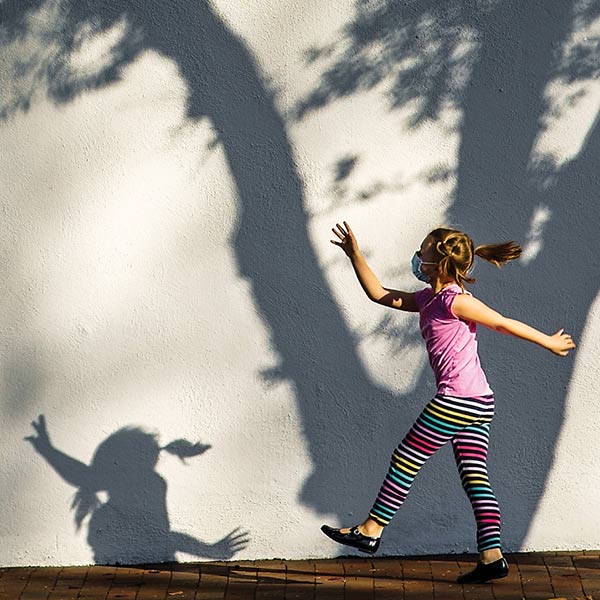 photo of a little girl walking happily on a sidewalk