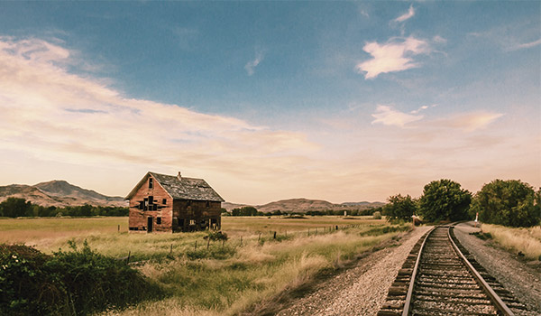 photo of train tracks going into the distance beside an old barn