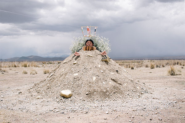 person in a pile of earth: reenactment of a painting of the Virgin of Potosi