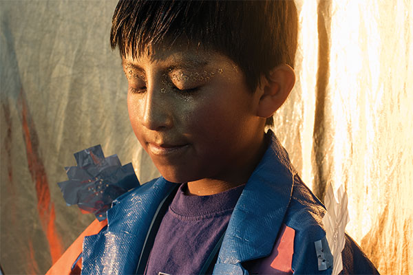 photograph of an Aymara boy with gold glitter and stars on his face