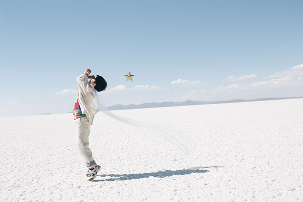 niño vestido de blanco bailando en un arenal: recreación de una imagen de El Principito