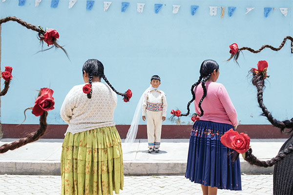 photograph of a group of Aymara women with roses woven in the end of their braids