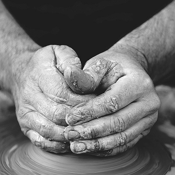 person forming clay on a potters wheel