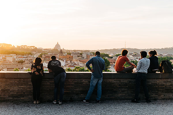 friends sitting and leaning on a wall looking at the view of an Italian city