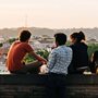friends sitting and leaning on a wall looking at the view of an Italian city