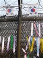 colorful ribbons with Korean writing on them tied on a barbed wire fence