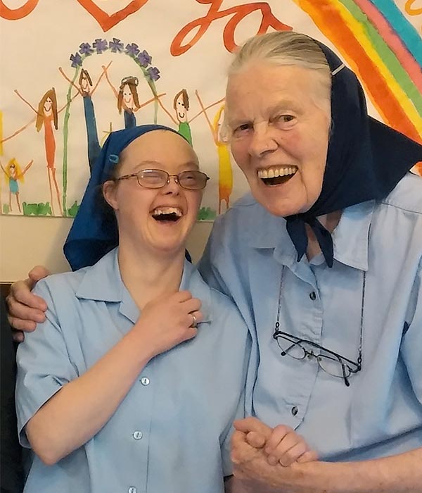 a young woman with Down syndrome sitting beside her elderly mother